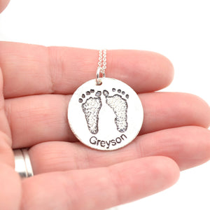 Etched foot print pendant in hand