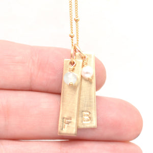 handstamped gold bar pendants in hand