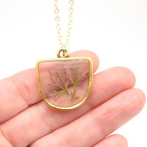 hand holding resin and leaf gold necklace