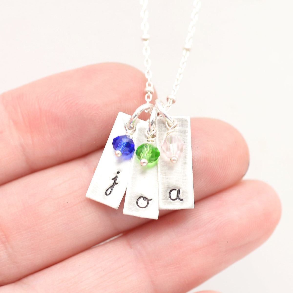 handstamped bar pendants with gemstones in hand