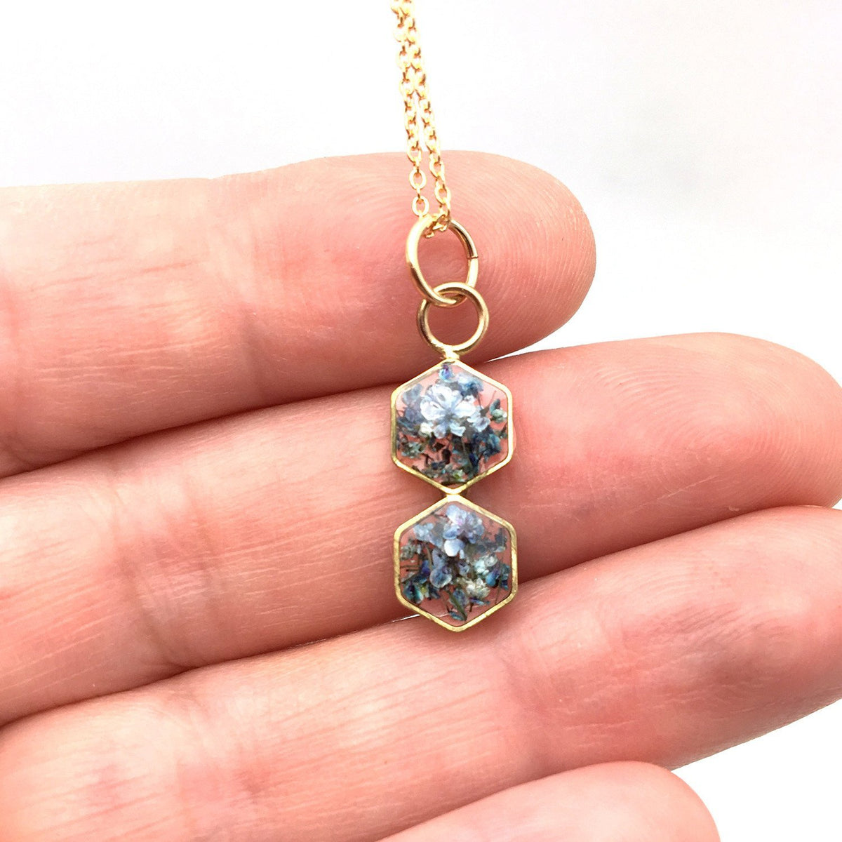 Dual hexagon floral necklace in gold in hand